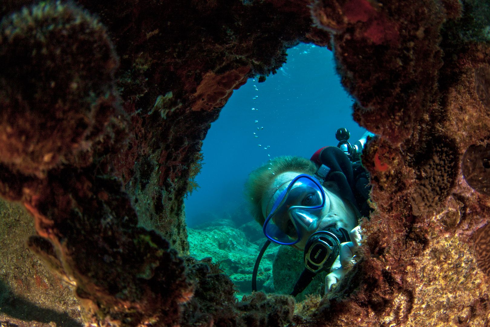 A diver looking through a hole in a shipwreck